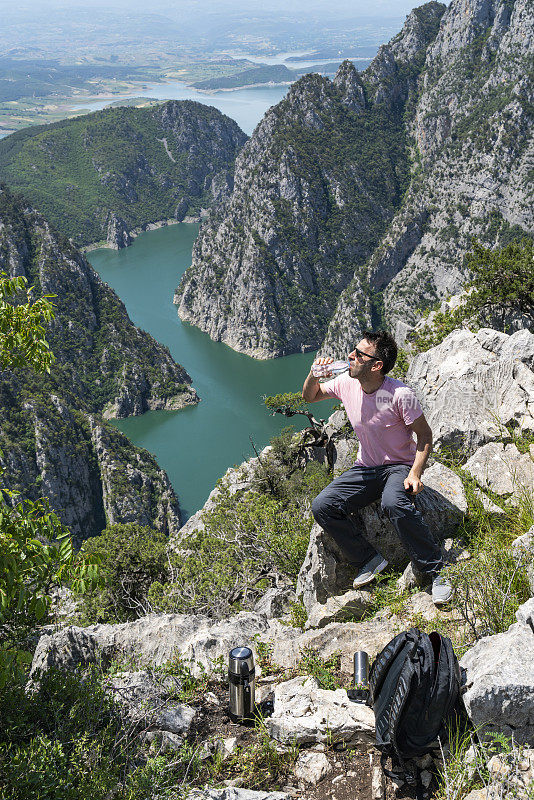 一名男子爬上了黑海地区Samsun省Vezürköprü Şahinkaya峡谷的顶峰，他坐在岩石上喝水。